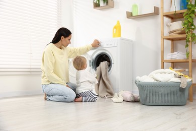Photo of Housewife with her baby doing laundry at home