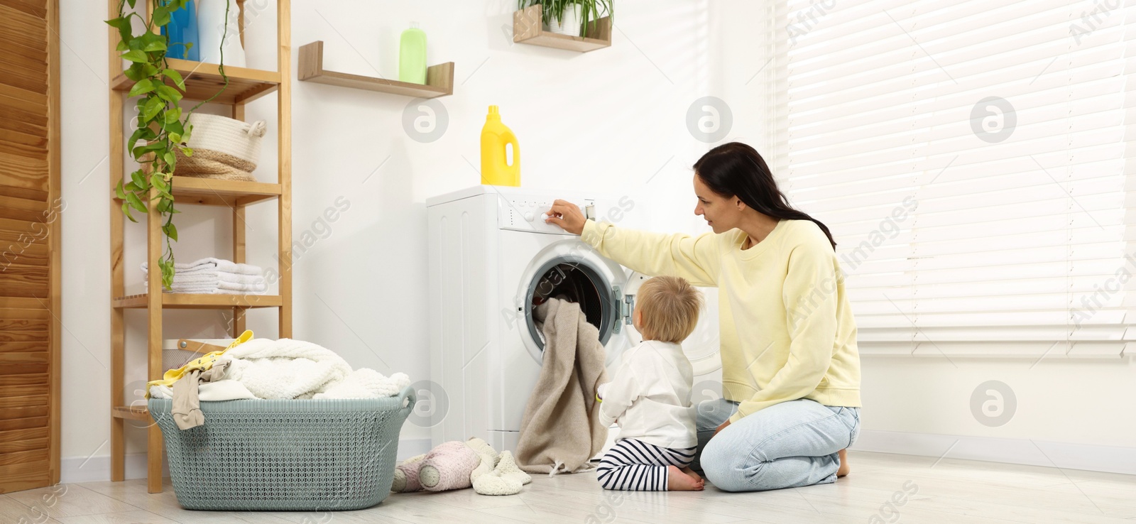 Photo of Housewife with her baby doing laundry at home