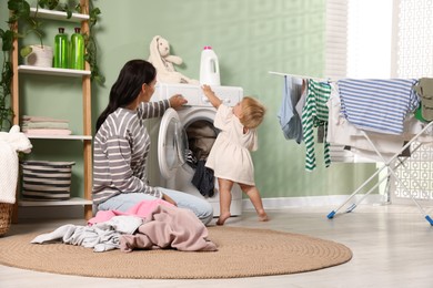 Photo of Mother with her little daughter doing laundry at home