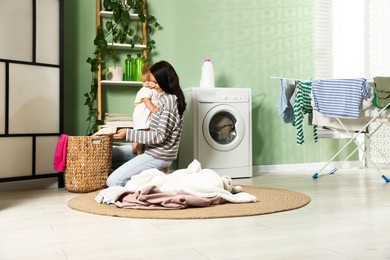 Photo of Smiling mother with her little daughter doing laundry at home