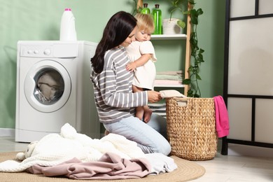 Photo of Mother with her little daughter doing laundry at home