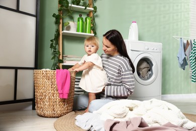 Photo of Mother with her little daughter doing laundry at home