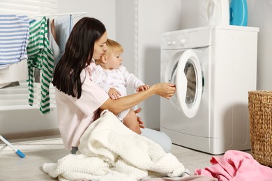 Photo of Mother with her little daughter doing laundry at home
