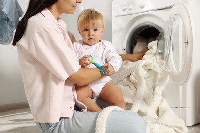 Photo of Mother with her little daughter doing laundry at home, closeup