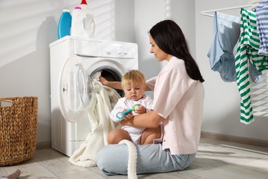 Photo of Mother with her little daughter doing laundry at home