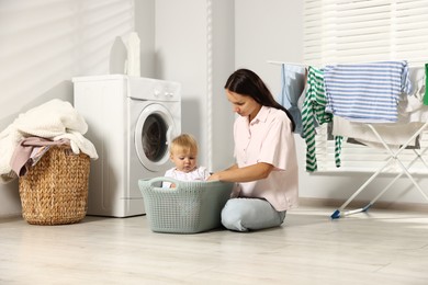 Photo of Mother with her little daughter doing laundry at home