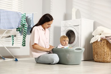 Photo of Mother with her little daughter doing laundry at home