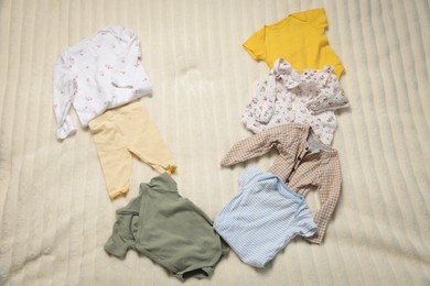 Photo of Different baby clothes on bed linens, top view