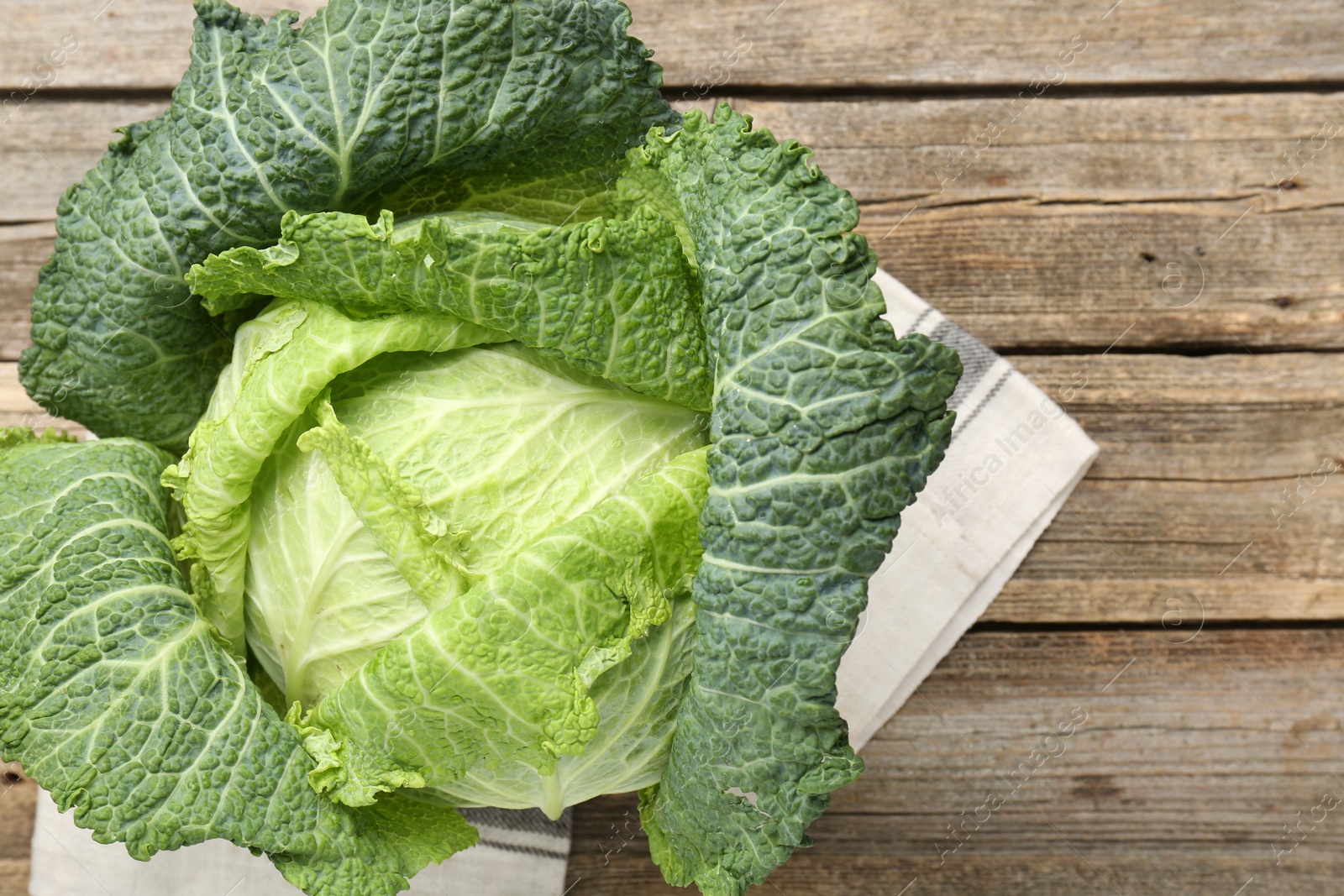 Photo of Fresh ripe Savoy cabbage on wooden table, top view. Space for text