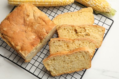 Photo of Freshly baked cut cornbread and cobs on white marble table, top view
