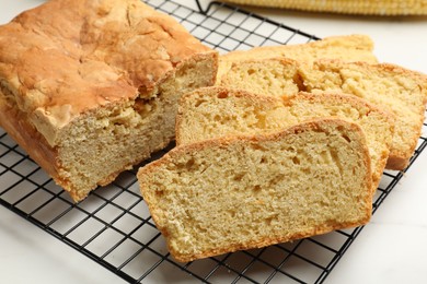 Photo of Freshly baked cut cornbread on white table, closeup