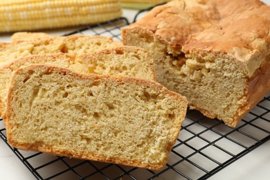 Photo of Freshly baked cut cornbread on white table, closeup