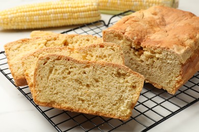 Photo of Freshly baked cut cornbread on white marble table, closeup