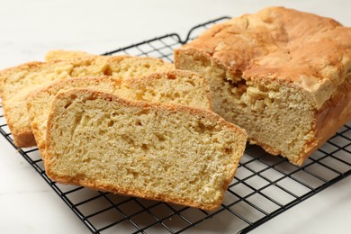 Photo of Freshly baked cut cornbread on white marble table, closeup