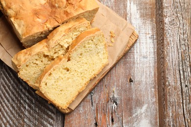 Photo of Freshly baked cut cornbread on wooden table, top view. Space for text