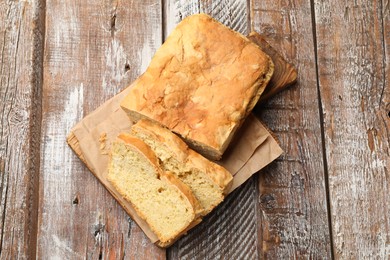 Photo of Freshly baked cut cornbread on wooden table, top view