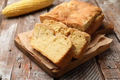 Photo of Freshly baked cut cornbread on wooden table, closeup