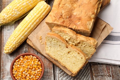 Photo of Freshly baked cut cornbread, cobs and seeds on wooden table, flat lay