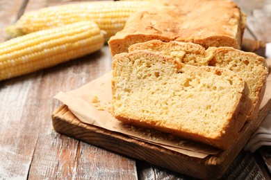 Photo of Freshly baked cut cornbread on wooden table, closeup