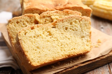 Photo of Freshly baked cut cornbread on wooden table, closeup