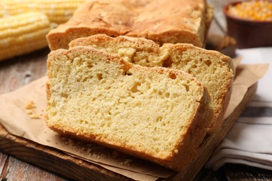 Photo of Freshly baked cut cornbread on wooden table, closeup