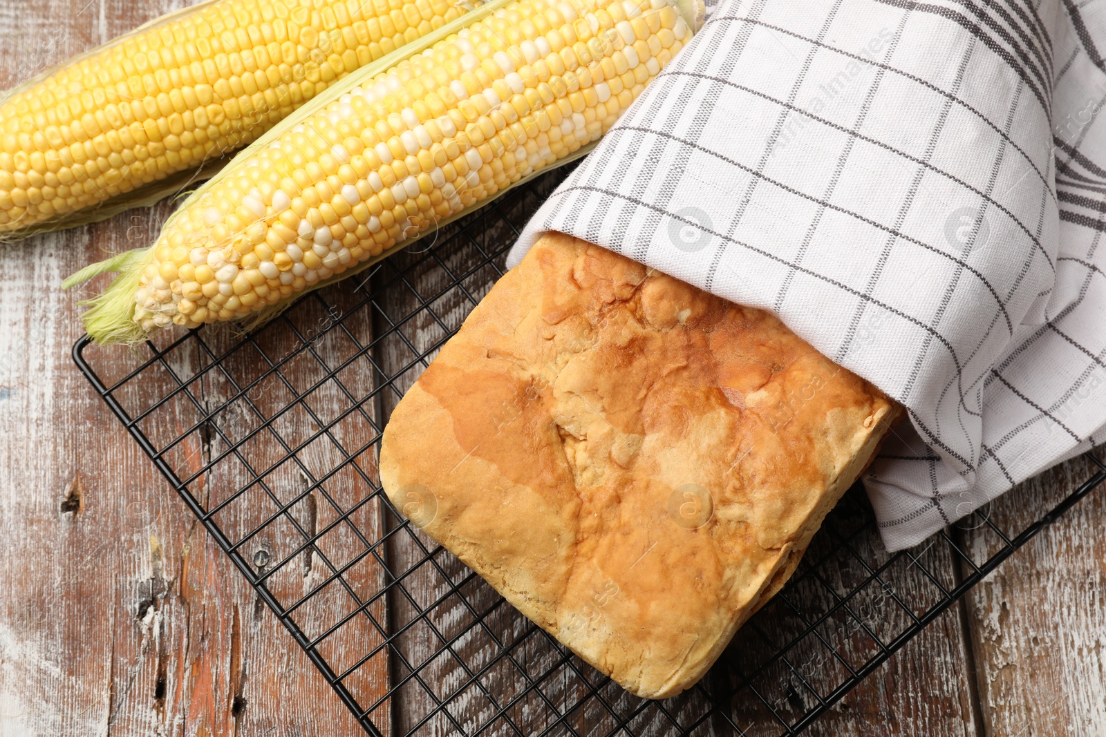 Photo of Freshly baked cornbread and cobs on wooden table, flat lay