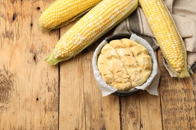 Photo of Freshly baked cornbread and cobs on wooden table, flat lay
