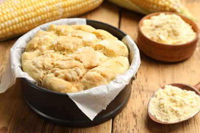 Photo of Freshly baked cornbread, flour and cobs on wooden table, closeup