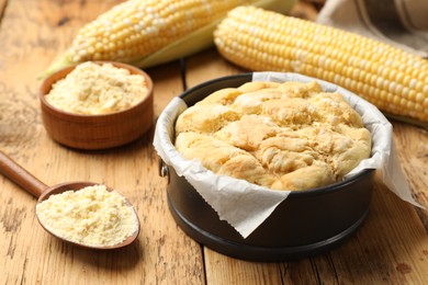 Photo of Freshly baked cornbread, flour and cobs on wooden table, closeup