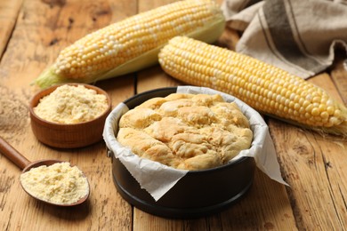 Photo of Freshly baked cornbread, flour and cobs on wooden table, closeup