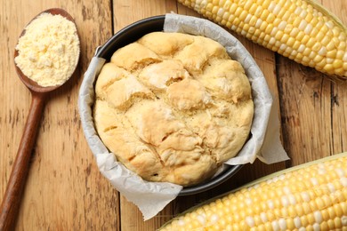 Photo of Freshly baked cornbread, flour and cobs on wooden table, flat lay