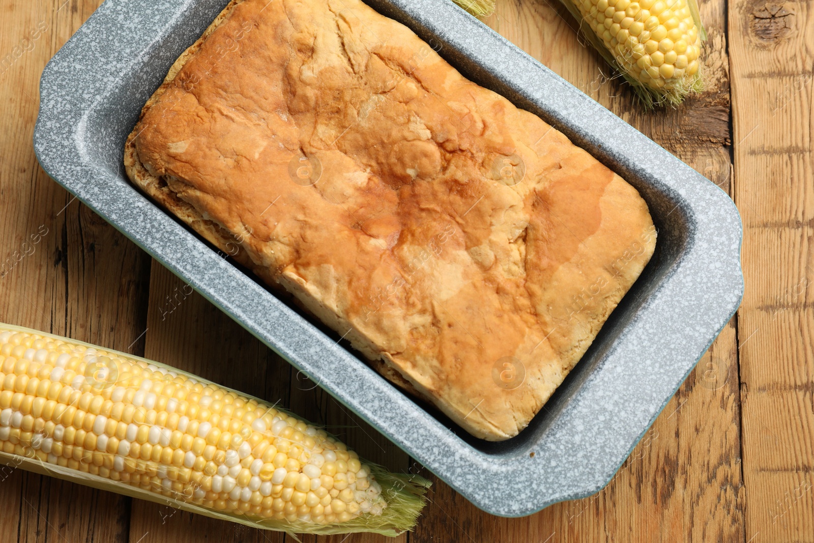 Freshly baked cornbread and cobs on wooden table, flat lay Photo of Freshly baked cornbread and cobs on wooden table, flat lay