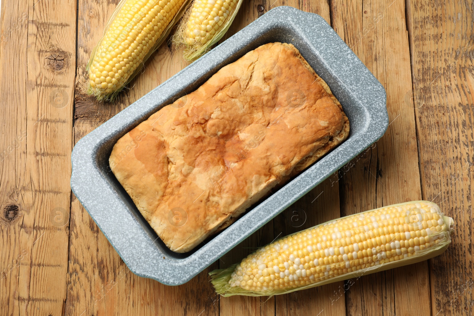 Freshly baked cornbread and cobs on wooden table, flat lay Photo of Freshly baked cornbread and cobs on wooden table, flat lay
