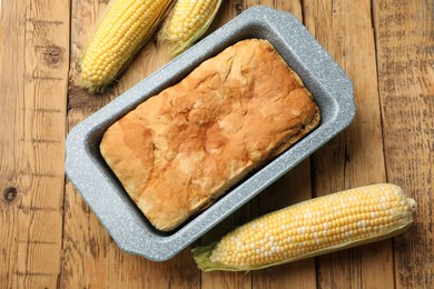 Photo of Freshly baked cornbread and cobs on wooden table, flat lay