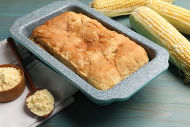 Photo of Freshly baked cornbread, flour and cobs on light blue wooden table, closeup