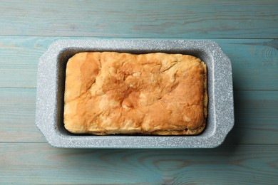 Photo of Freshly baked cornbread in baking dish on light blue wooden table, top view