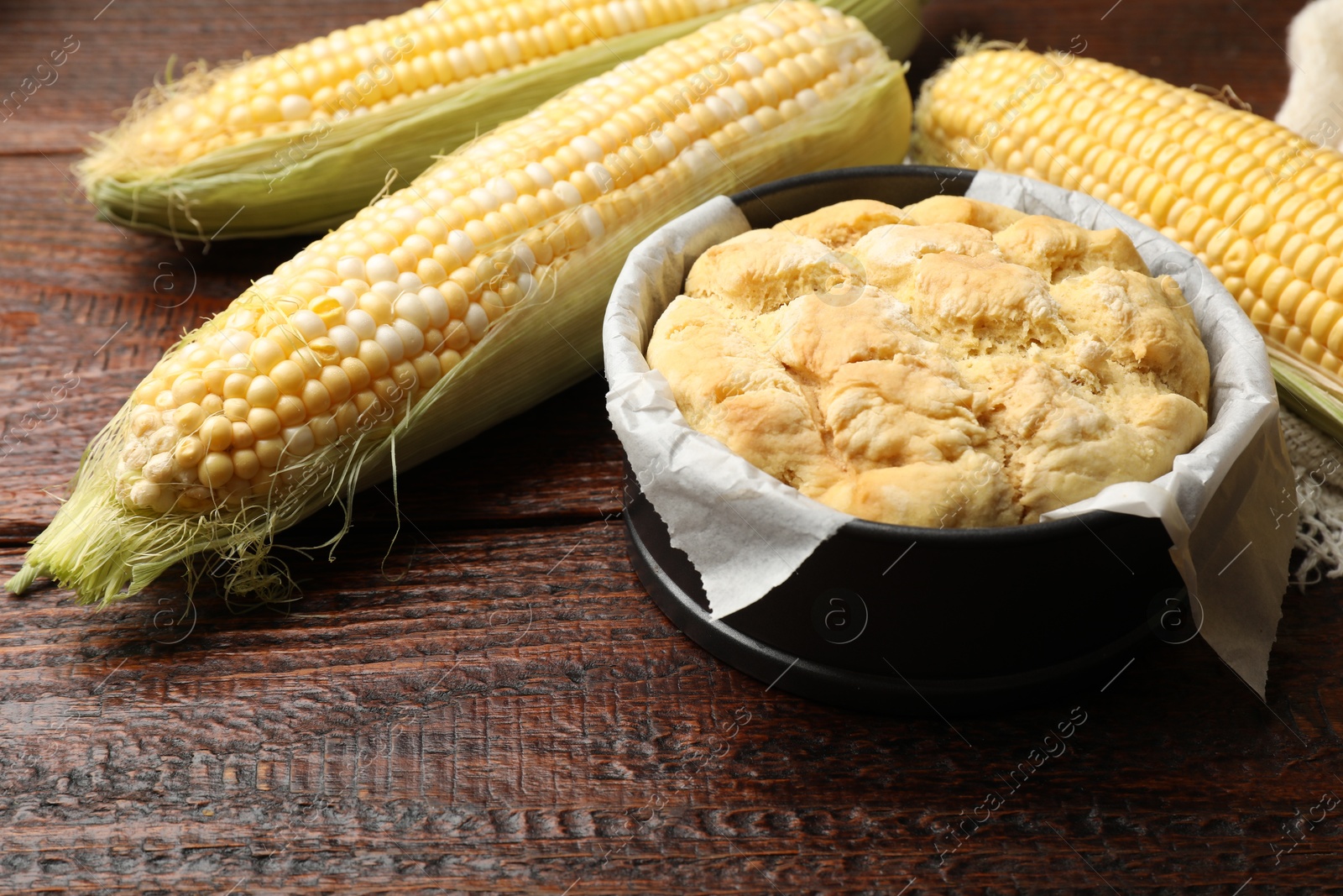 Photo of Freshly baked cornbread and cobs on wooden table, closeup
