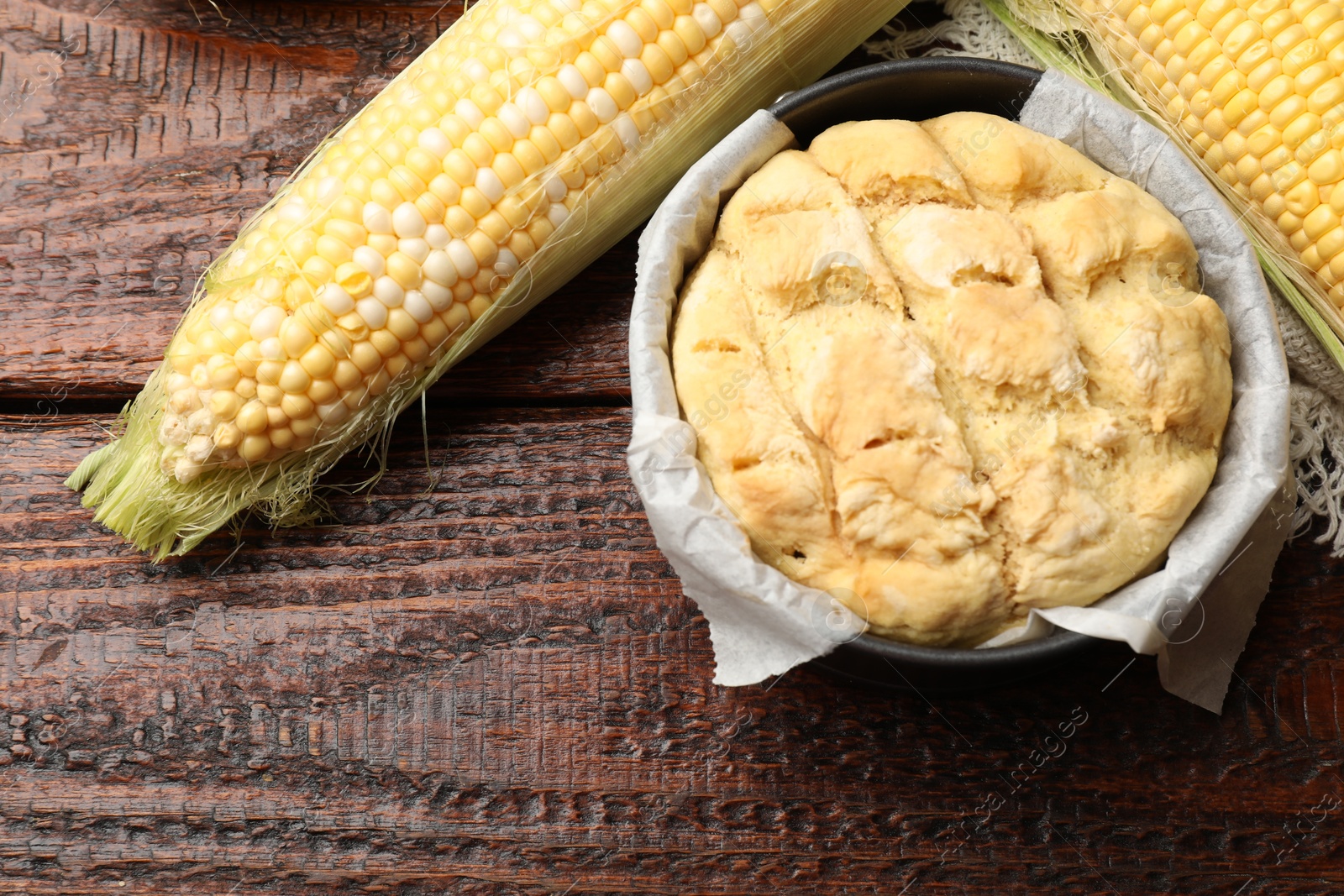 Photo of Freshly baked cornbread and cobs on wooden table, flat lay