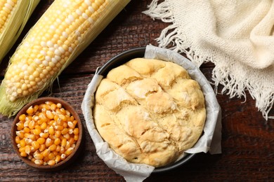 Photo of Freshly baked cornbread, seeds and cobs on wooden table, flat lay