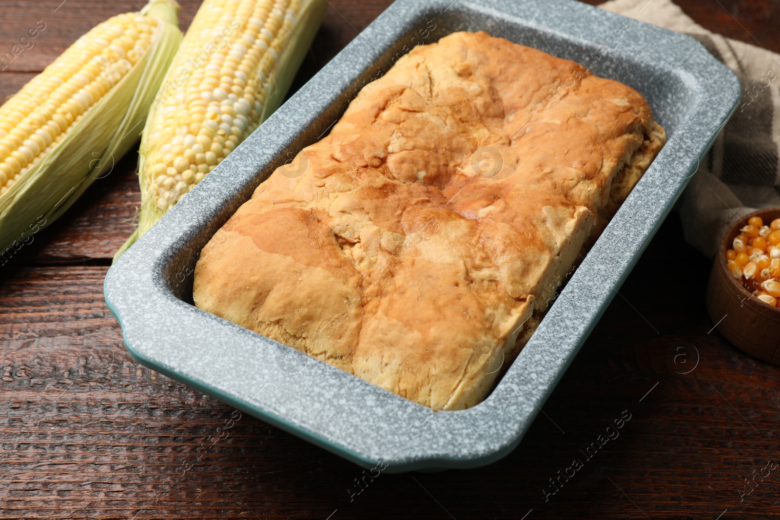 Photo of Freshly baked cornbread, seeds and cobs on wooden table, closeup