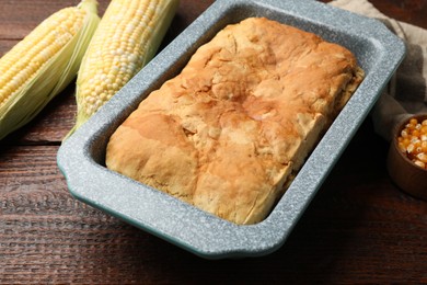 Photo of Freshly baked cornbread, seeds and cobs on wooden table, closeup