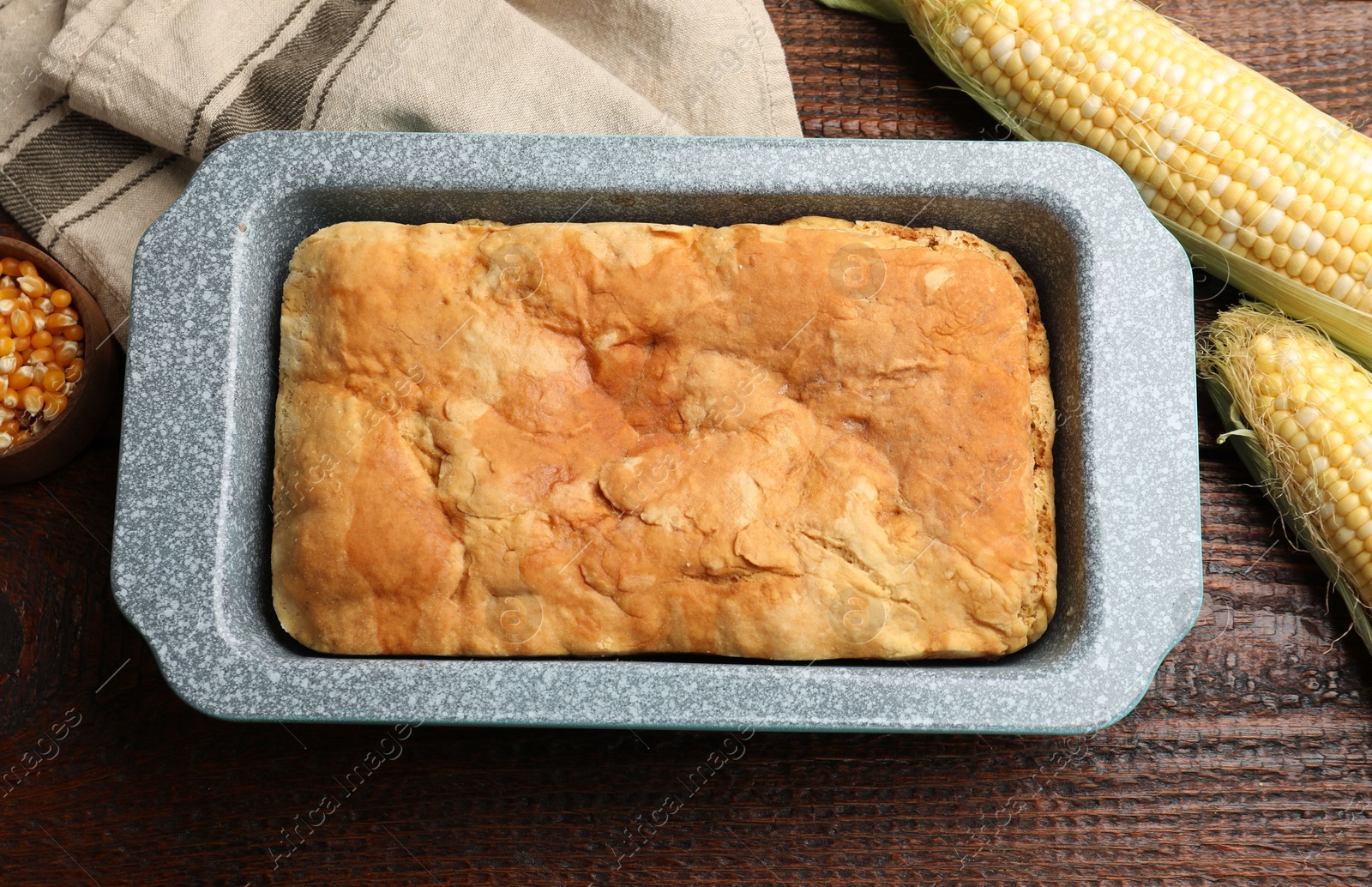 Photo of Freshly baked cornbread, seeds and cobs on wooden table, flat lay