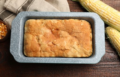 Photo of Freshly baked cornbread, seeds and cobs on wooden table, flat lay