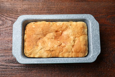 Photo of Freshly baked cornbread in baking dish on wooden table, top view