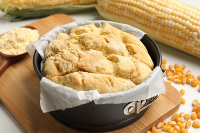 Photo of Freshly baked cornbread, seeds, flour and cobs on white table, closeup
