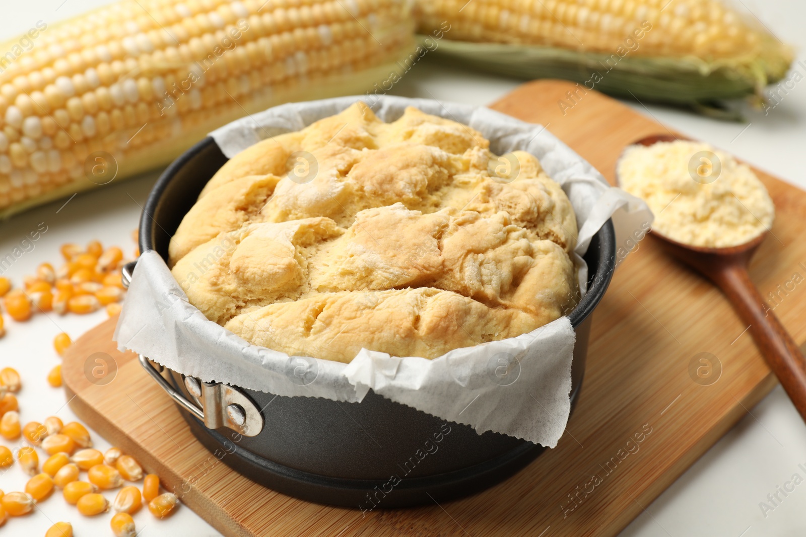 Freshly baked cornbread, seeds, flour and cobs on white table, closeup Photo of Freshly baked cornbread, seeds, flour and cobs on white table, closeup