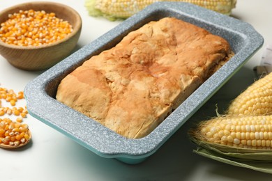 Photo of Freshly baked cornbread, seeds and cobs on white marble table, closeup