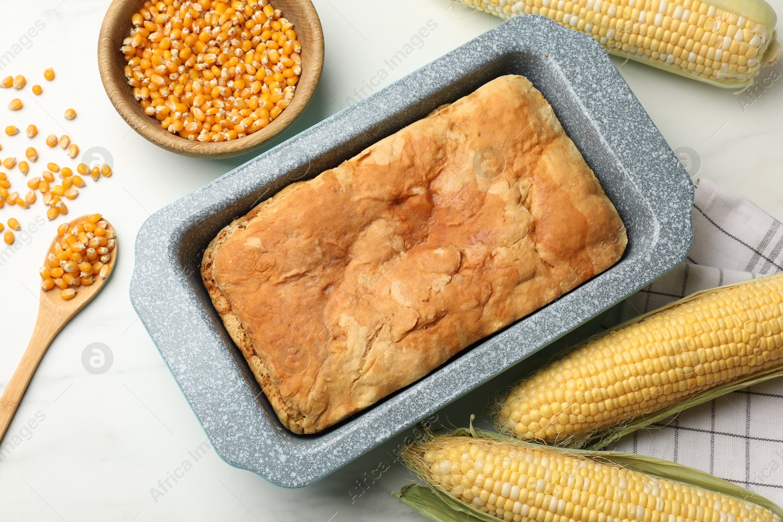 Freshly baked cornbread, seeds and cobs on white marble table, flat lay Photo of Freshly baked cornbread, seeds and cobs on white marble table, flat lay