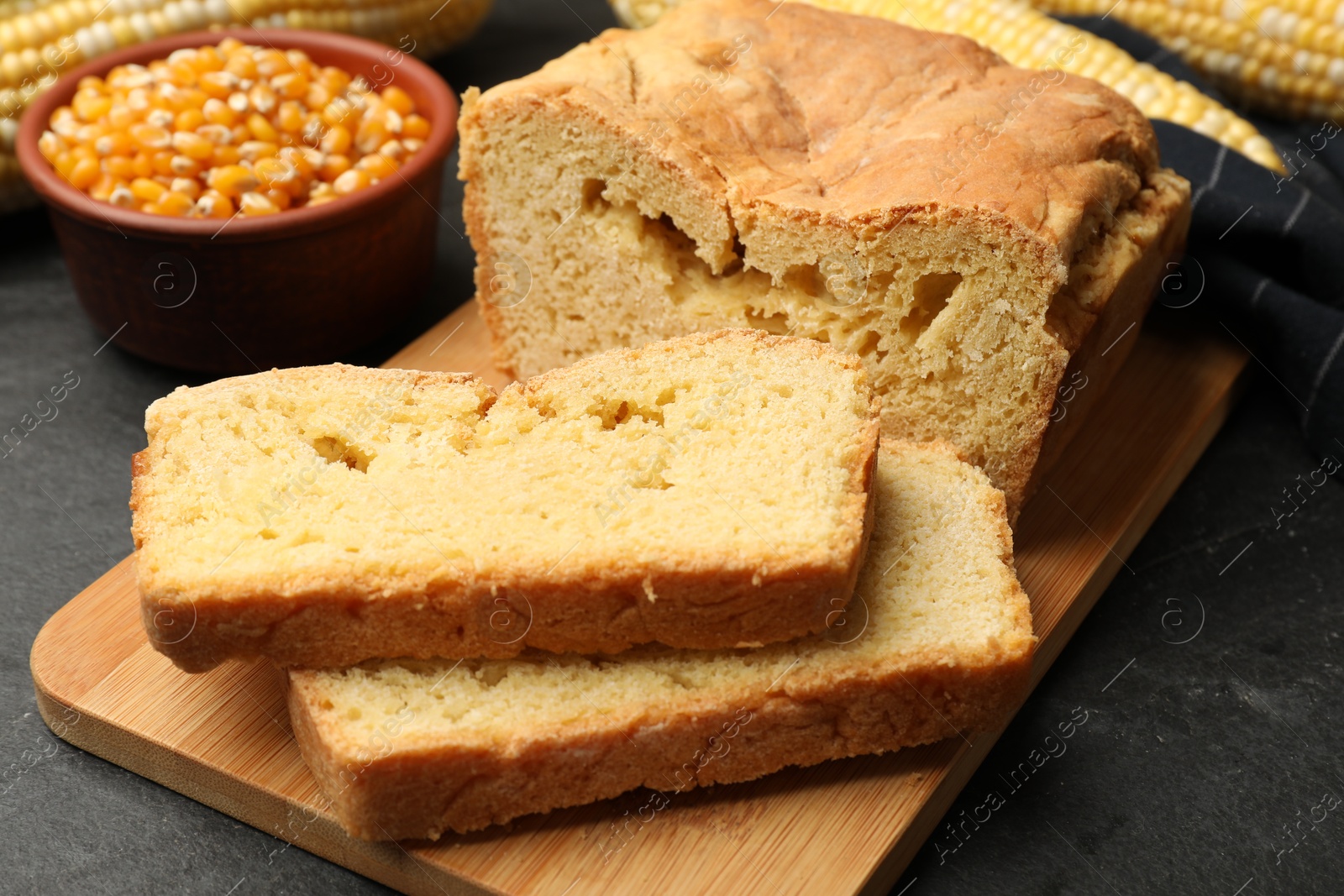 Freshly baked cornbread, cobs and seeds on black table, closeup Photo of Freshly baked cornbread, cobs and seeds on black table, closeup
