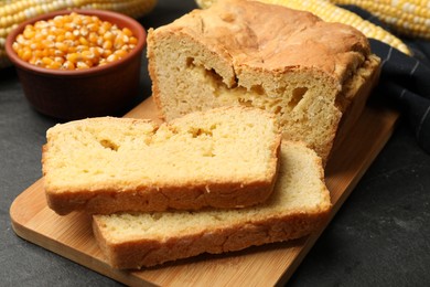 Photo of Freshly baked cornbread, cobs and seeds on black table, closeup